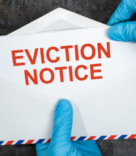 Close-up Of A Person's Hand Holding Eviction Notice In Red Envelope